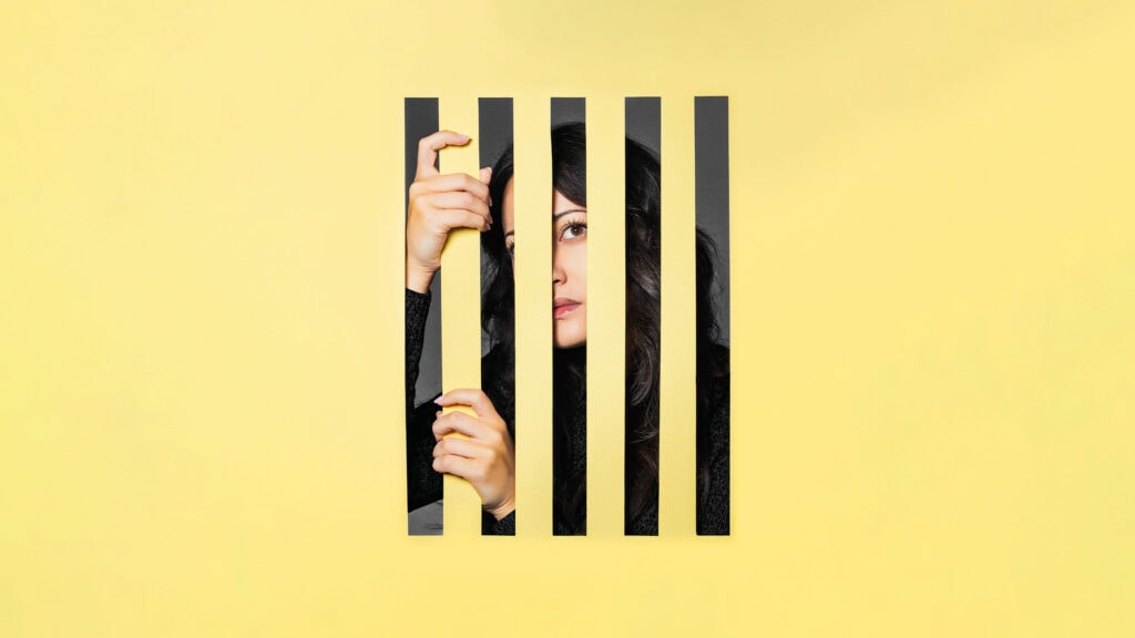 Artwork for English Touring Opera Manon Lescaut, a woman is behind yellow bars.
